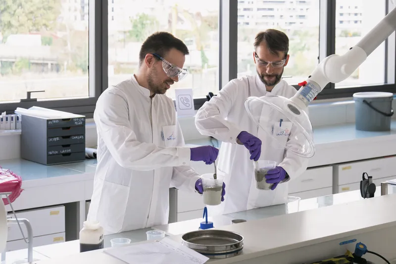 Two researchers in lab coats handling samples at a laboratory bench, photographed for Microsoft